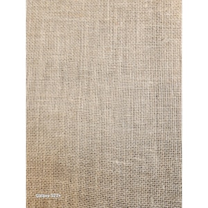 May include: Close-up of a beige burlap fabric with a coarse, woven texture. The natural fibers create a grid-like pattern, ideal for rustic crafts and home decor projects. The fabric is tightly woven and appears durable.