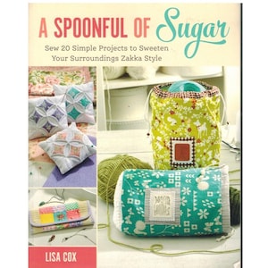 May include: A book cover titled "A Spoonful of Sugar" with text that reads "Sew 20 Simple Projects to Sweeten Your Surroundings Zakka Style." The image shows handmade items like pillows, a drawstring bag, and a small case. The author's name, Lisa Cox, is at the bottom.