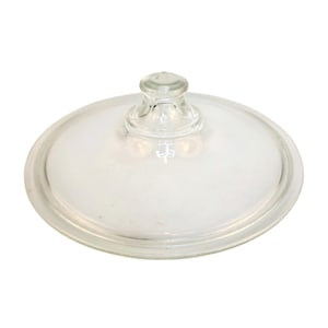 May include: A clear glass lid with a rounded shape and a small, rounded handle on top. The lid is transparent, allowing a view of what it covers. The design is simple and functional, suitable for kitchen use.