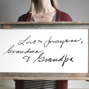 May include: A framed white canvas with black handwritten text that reads "Love & prayers, Grandma & Grandpa".