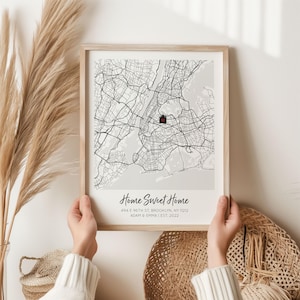 May include: A framed map print of Brooklyn, New York, with a red marker indicating a specific location. The print includes the text "Home Sweet Home," address, and the names Adam & Emma with the year 2022.