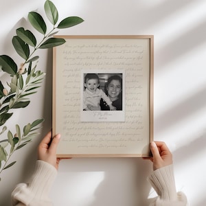May include: A rectangular framed print featuring a beige background with cursive text and a centered black and white square photograph of a child and an adult. The text reads To My Mama and includes the date 08.07.24 below the photograph.