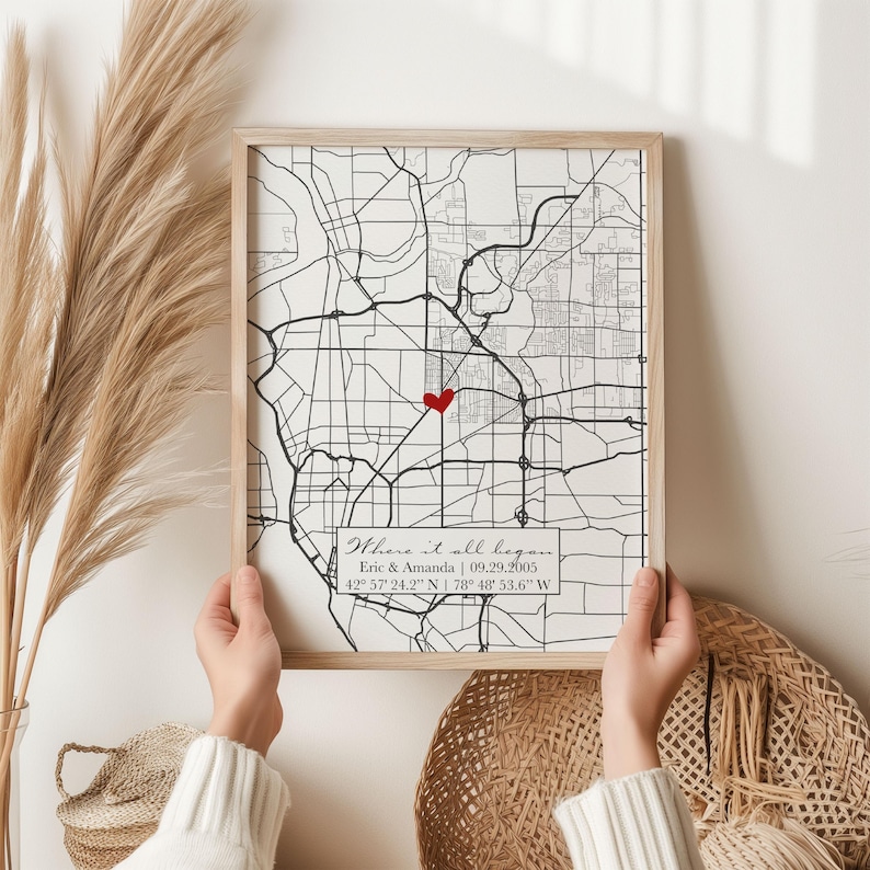 May include: A framed black and white map with a red heart marking a location. The map has the text "Where it all began" with the names Eric & Amanda and the date 09.29.2005. The coordinates 42&deg; 57' 24.2" N 178&deg; 48' 53.6" W are also included.