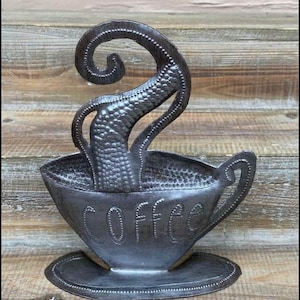 May include: A metal sculpture of a coffee cup with steam rising from it. The cup is black and has the word "COFFEE" written on it.