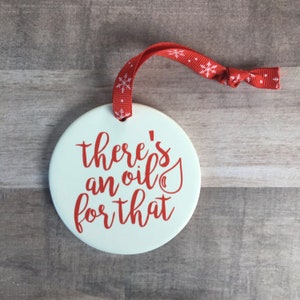 May include: White ceramic ornament with red text that reads "there's an oil for that" and a red oil drop icon.