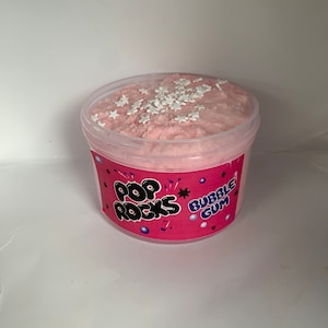 May include: Pink slime with white star sprinkles in a clear plastic container with a pink and white label that says "Pop Rocks Bubble Gum".