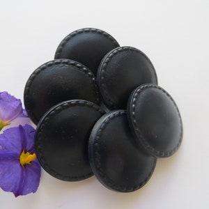 May include: Six black round buttons with a raised, textured edge. The buttons are arranged in a semi-circle.