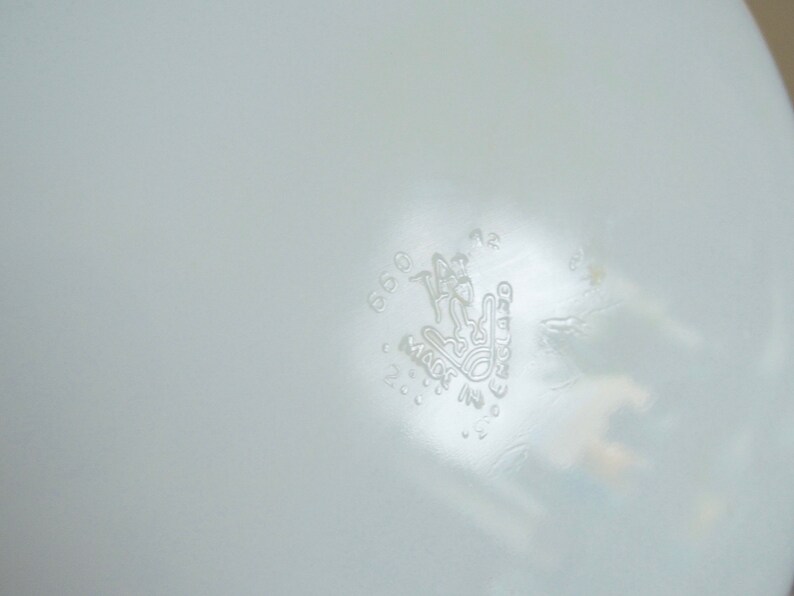 Peut inclure: Gros plan sur un objet blanc, l&eacute;g&egrave;rement translucide, avec un motif en relief. Le motif comprend les mots "MADE IN FRANCE" et une image stylis&eacute;e d'une personne. L'objet a une surface lisse.