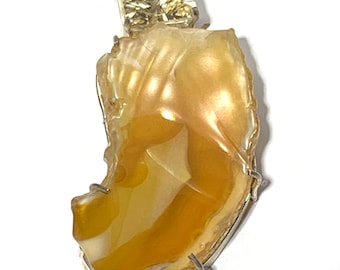 May include: A silver chain necklace with a pendant featuring a large, irregularly shaped, yellow agate stone set in silver. A smaller, square-shaped, clear gemstone is set above the agate.