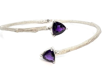 May include: A silver bangle bracelet with a twig design and two purple amethyst gemstones.