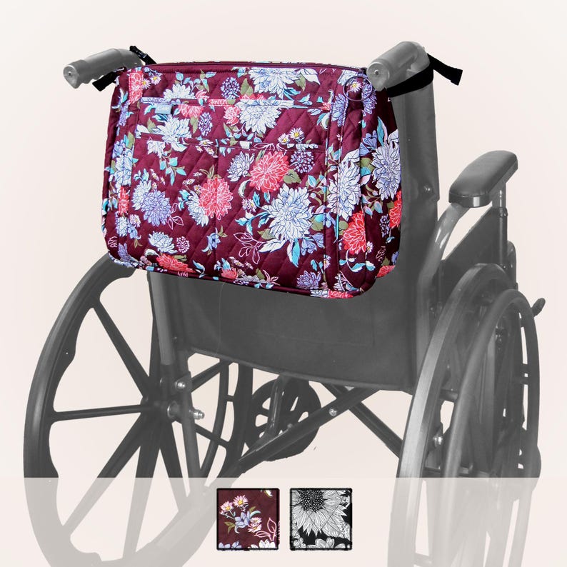 May include: A floral patterned wheelchair bag with a zipper closure and multiple pockets. The bag is attached to the back of a wheelchair.