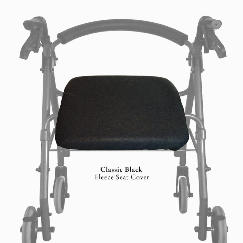 Puede incluir: Una funda de asiento de forro polar negro colocada en un andador con cuatro ruedas y respaldo curvo. El texto Classic Black Fleece Seat Cover est&aacute; impreso debajo del asiento. El marco del andador es negro con un asa acolchada.