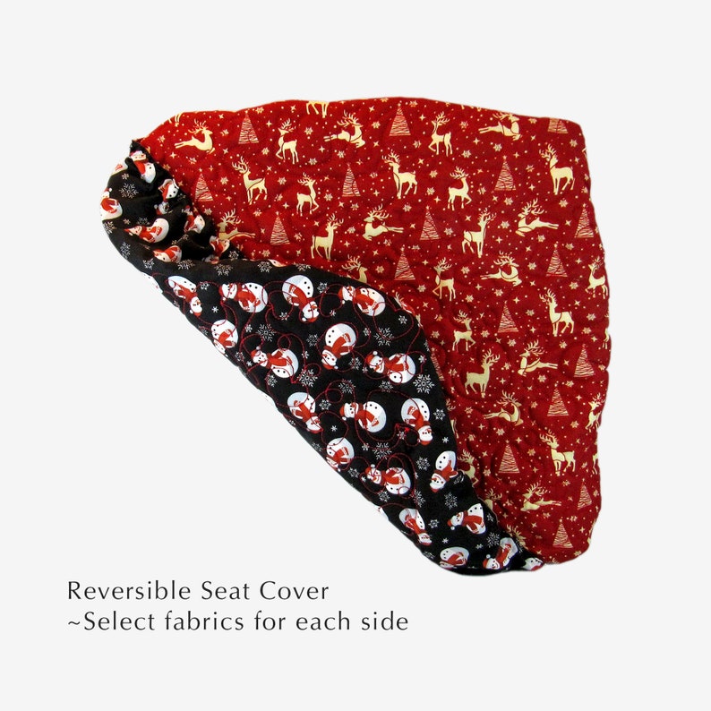 May include: Reversible seat cover with two different Christmas-themed fabric designs. One side features a red background with gold reindeer and Christmas trees. The other side features a black background with white snowmen and snowflakes. "Reversible Seat Cover - Select fabrics for each side" is written below the image.