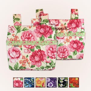 May include: Two quilted fabric organizers with a floral pattern featuring large pink peonies and green leaves. The organizers have pockets and straps. The word "ana" is written on one of the organizers. The bottom of the image shows fabric swatches.