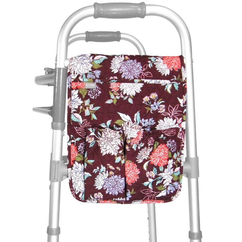 May include: A floral patterned walker bag with multiple pockets. The bag is attached to a walker with a silver frame.