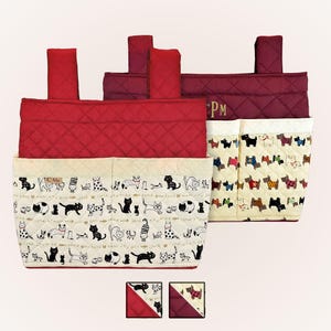May include: Red and cream quilted fabric organizer with pockets. The organizer features a cat print and a dog print. The top is a solid red quilted fabric. The organizer has a handle on each side. The initials "PM" are embroidered on the side.