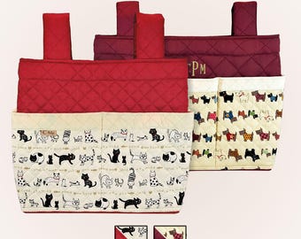 May include: Red and cream quilted fabric organizer with pockets. The organizer features a cat print and a dog print. The top is a solid red quilted fabric. The organizer has a handle on each side. The initials "PM" are embroidered on the side.