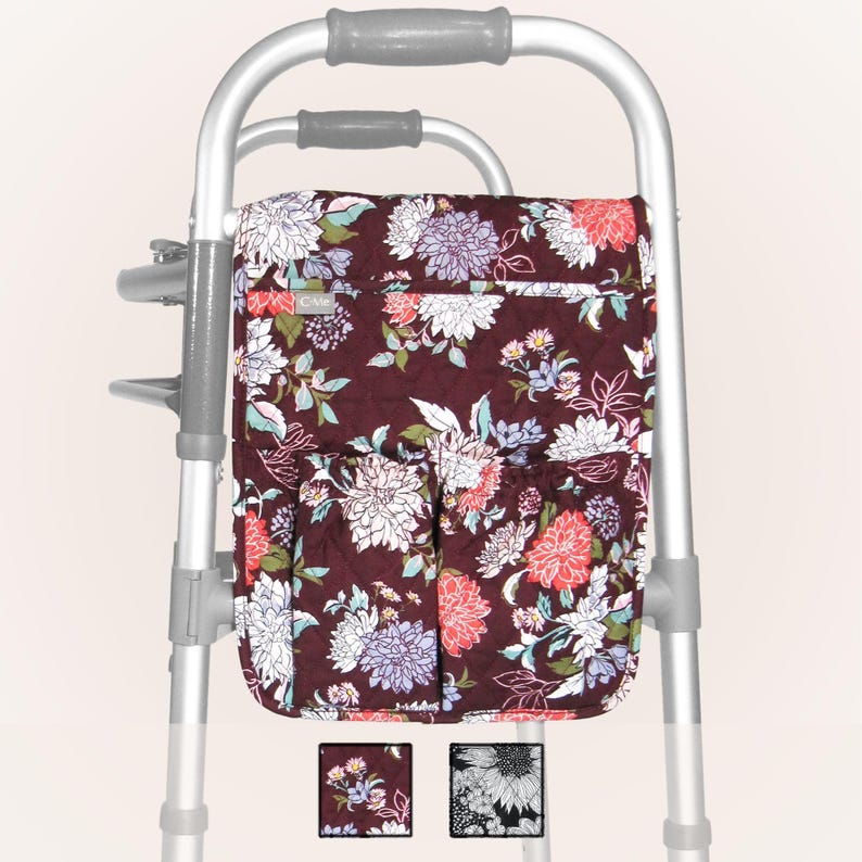 May include: A floral patterned walker bag with multiple pockets. The bag is attached to a silver walker. The bag is quilted and has a zipper closure. The bag is available in two colors: burgundy with white and pink flowers and black with white flowers.