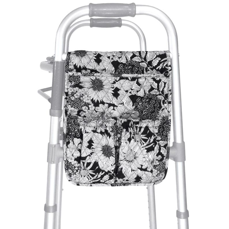 May include: A black and white floral walker bag with multiple pockets. The bag is attached to a silver walker.