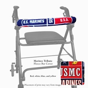 Pode incluir: Um andarilho de metal preto com uma capa de barra em tecido polar com um padr&atilde;o vermelho, branco, azul e amarelo. A capa exibe o texto U.S. MARINES, U.S.A. e USMC. O andarilho inclui um assento preto e rodas, com detalhe da estampa.
