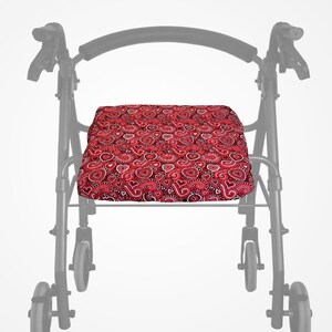 May include: A red and white heart-patterned seat cushion for a walker. The cushion is rectangular and features a repeating design of hearts and paisley shapes. The walker frame is visible in the background.