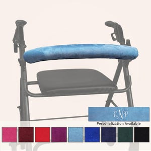 Pode incluir: Uma capa de pelúcia azul-claro para o encosto de um andador, com textura macia. Uma amostra retangular mostra o tecido azul com as letras do monograma brancas ENP e o texto Personalization Available abaixo.