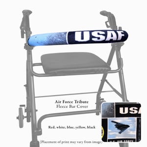 Pode incluir: Um andarilho preto com uma capa de barra em tecido polar acolchoado, apresentando uma estampa azul, branca e preta com o texto USAF e um gr&aacute;fico de avi&atilde;o. A capa envolve a barra horizontal do andarilho, que inclui um assento preto.