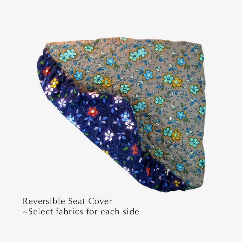 May include: Reversible seat cover with a floral pattern on both sides. One side is a dark blue fabric with white, red, and yellow flowers. The other side is a light gray fabric with blue, yellow, and orange flowers. "Reversible Seat Cover - Select fabrics for each side" is written below the image.