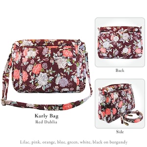 May include: A burgundy quilted shoulder bag with a floral print featuring red, white, and pink flowers. The bag has a long adjustable strap and multiple pockets. The bag is called "Karly Bag" and the print is called "Red Dahlia".