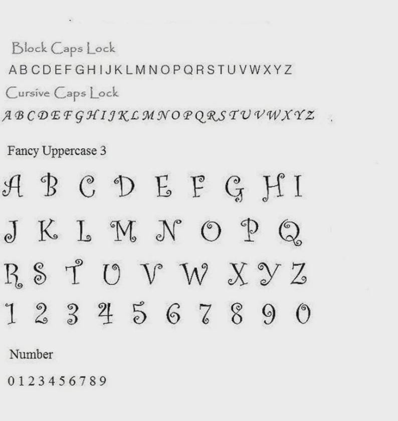 May include: A white sheet displays various font styles, including block, cursive, and fancy uppercase letters and numbers. The fonts are in black, showcasing different design options for text.