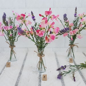 May include: Three glass vases filled with pink and white sweet pea flowers and purple lavender. The vases are tied with twine and are numbered 1, 2, and 3.