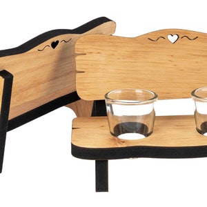 May include: Wooden bench shot glass holder with two clear shot glasses. The bench has a black trim and a heart cutout on the back.