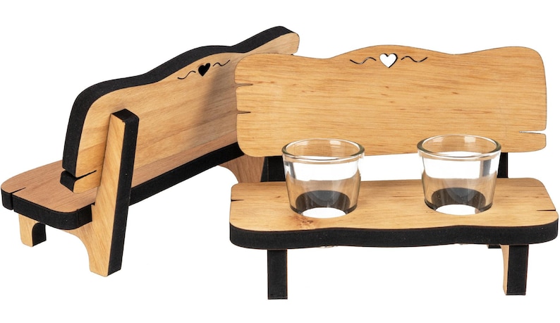 May include: Wooden bench shot glass holder with two clear shot glasses. The bench has a black trim and a heart cutout on the back.