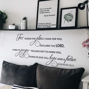 Puede incluir: Un dormitorio con una cama blanca, almohadas a rayas blancas y negras y una almohada gris con un diseño de ciervo. La pared sobre la cama tiene una cita en blanco y negro que dice "Porque yo sé los planes que tengo para vosotros, declara Jehová, planes de bien y no de mal, para daros un futuro y una esperanza. Jeremías 29:11".