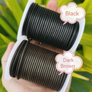 A hand holding two spools of black and brown leather cord, with speech bubbles indicating the color of each spool.