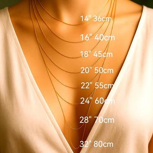 a close-up of a person's neck with multiple gold necklaces of varying lengths, each labeled with its corresponding size in centimeters.