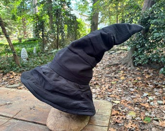 May include: A black witch hat with a tall, pointed crown and a wide brim. The hat is made of a soft, fabric material and has a slightly wrinkled texture.