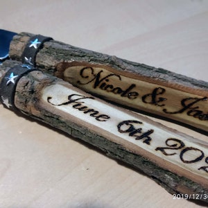 May include: A pair of wooden cake cutting knives with black leather handles and silver stars. The handles are engraved with "Nicole & Jason" and "June 6th 2020".