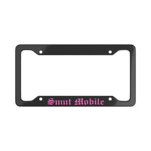 Puede incluir: Un marco negro para matrícula con las palabras "Smut Mobile" en rosa con fuente gótica. El marco tiene cuatro orificios de montaje y un acabado brillante. El texto está centrado en la parte inferior.