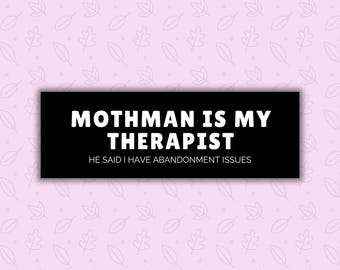 May include: A black rectangle with the text "MOTHMAN IS MY THERAPIST" in white, with the text "HE SAID I HAVE ABANDONMENT ISSUES" below it. The background is light pink with a pattern of leaves.