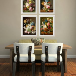 May include: Four framed floral still life paintings with white frames and a light brown background. The paintings are arranged in a grid pattern on the wall above a wooden table with two chairs.
