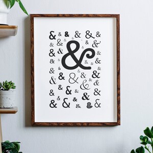 May include: A framed print with a white background and a black ampersand symbol repeated in various styles and sizes.