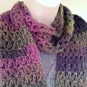 May include: A multi-colored crocheted scarf with shades of pink, purple, green, and brown. The scarf is made with a chunky yarn and has a loose, open weave.