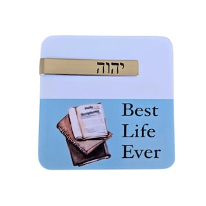 May include: A white square magnet with a silver bar that says "יהוה" in Hebrew. The magnet also has a blue background with a drawing of two books and the text "Best Life Ever".