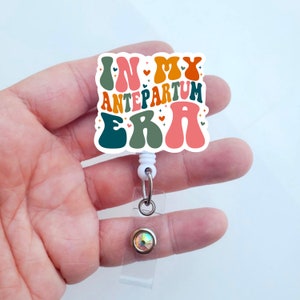 May include: A white retractable badge holder with a colorful "In My Antepartum Era" graphic. The graphic features a retro font and colorful hearts and stars.