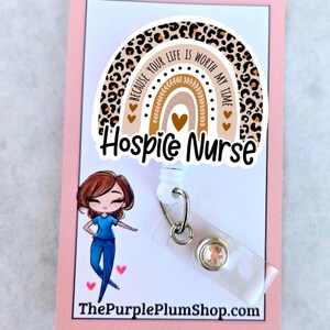 May include: A white retractable badge holder with a leopard print rainbow charm. The charm has the text "Because your life is worth my time" and "Hospice Nurse". The badge holder has a clear plastic badge holder and a sparkly rhinestone.