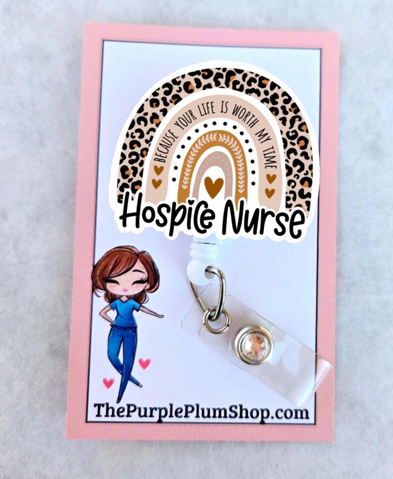 May include: A white retractable badge holder with a leopard print rainbow charm. The charm has the text "Because your life is worth my time" and "Hospice Nurse". The badge holder has a clear plastic badge holder and a sparkly rhinestone.