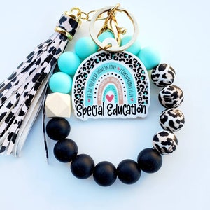 May include: A keychain with a black and white leopard print tassel, black and turquoise beads, and a white and turquoise rainbow charm with the text "Let all you do be done in love 1 Corinthians 16:14" and "Special Education".