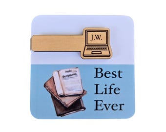 May include: Wooden bookmark with a laptop design and the initials "J.W." engraved on it. The bookmark is placed on a blue background with a stack of books and the text "Best Life Ever".