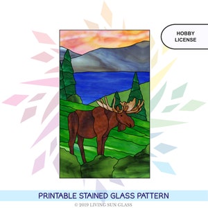 May include: Printable stained glass pattern of a moose standing in a forest with a lake and mountains in the background. The pattern is for hobby use only.